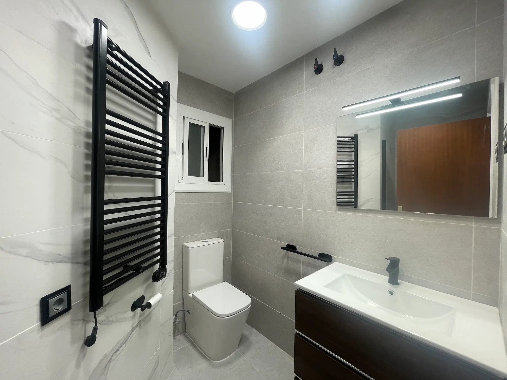 Baño reformado con revestimiento de mármol.